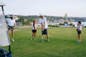 Family day at the golf course with parents teaching kids to play golf with a beautiful scenic view.