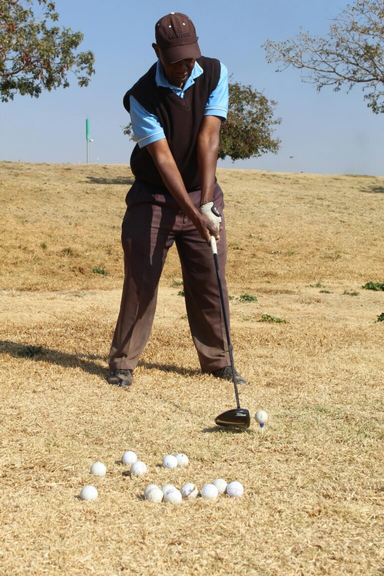 Golfer practicing swing in Soweto on dry grass field, sunny day.