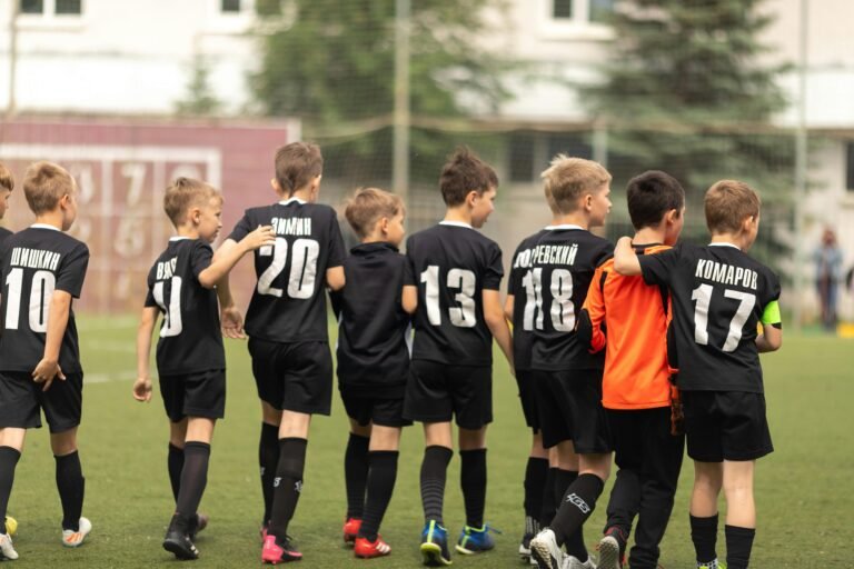 A group of young soccer players celebrating victory on the football field.