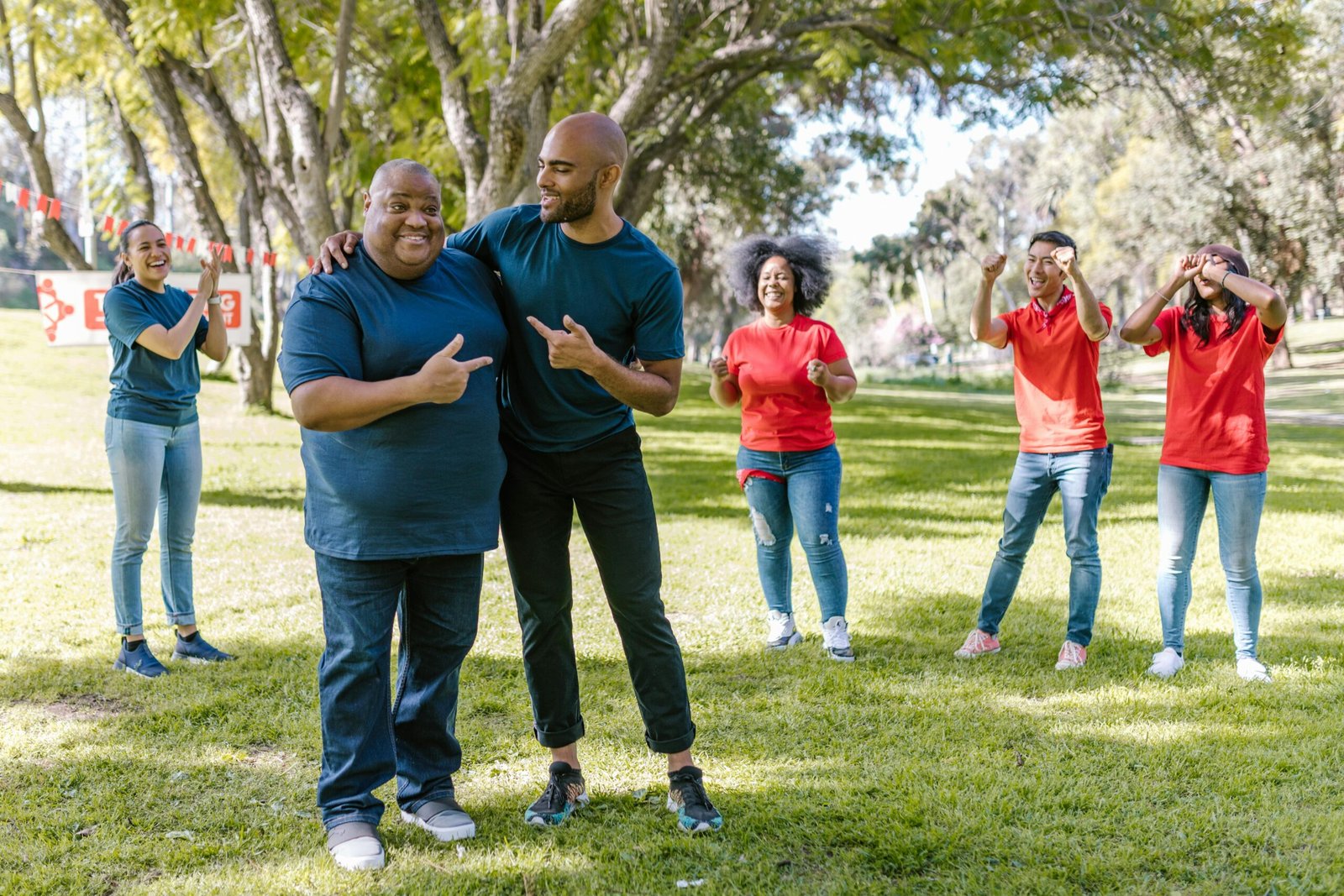 Group of adults engaging in fun team building activities in a sunny park, showcasing teamwork and diversity.