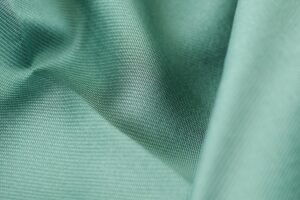 Detailed close-up shot of smooth green silk fabric texture showcasing softness and elegance.