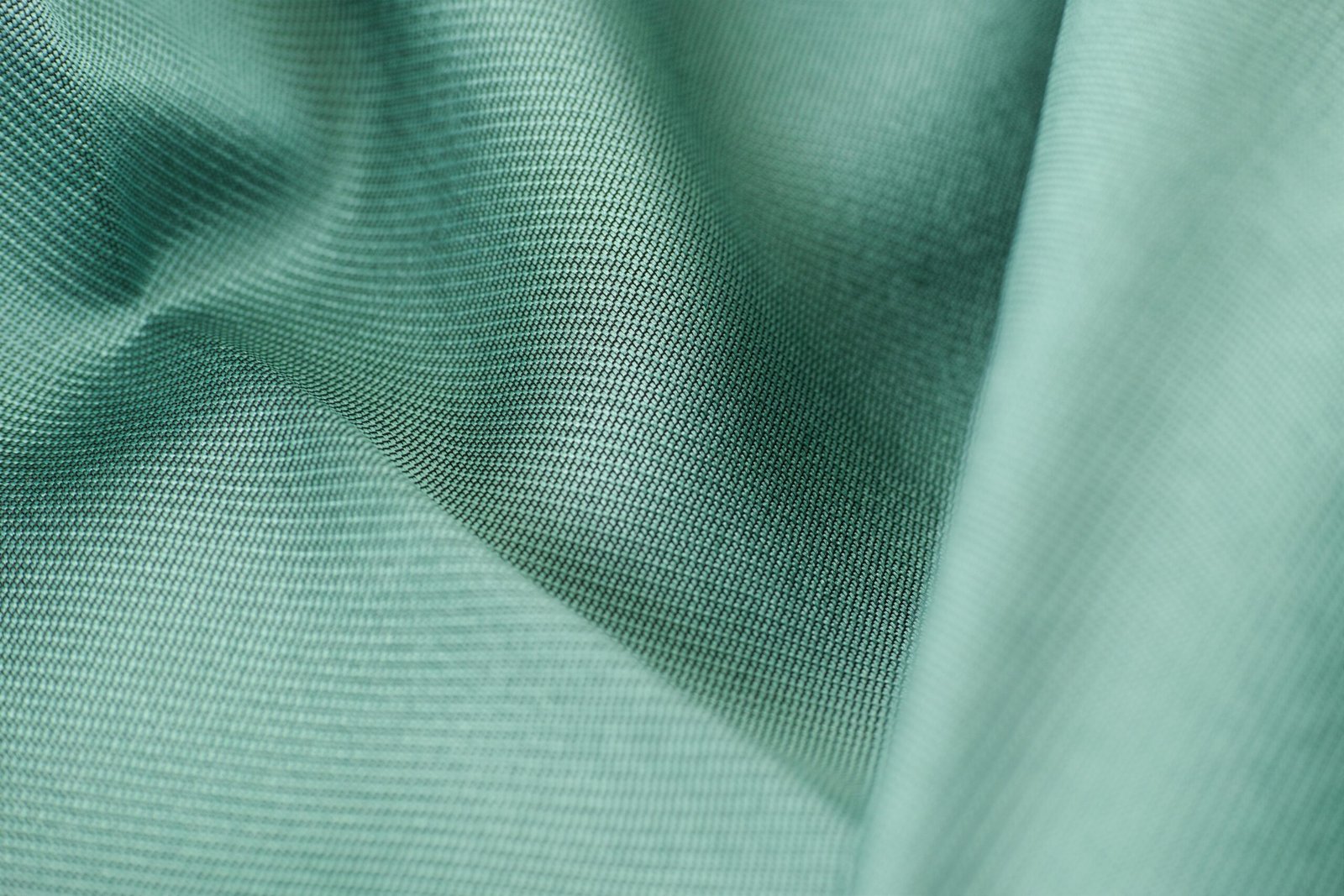 Detailed close-up shot of smooth green silk fabric texture showcasing softness and elegance.