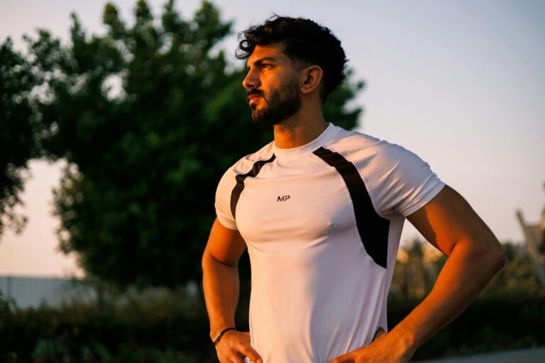 Athletic man in a white shirt stands confidently during sunrise in Jeddah, Saudi Arabia.
