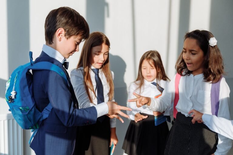 Group of diverse school children in uniform playing rock paper scissors indoors.
